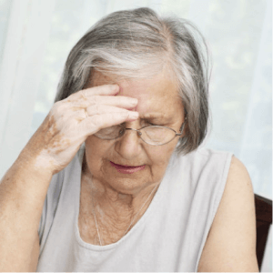An elderly woman holding her head