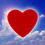 Picture of a red heart against a background of a blue sky and white clouds.