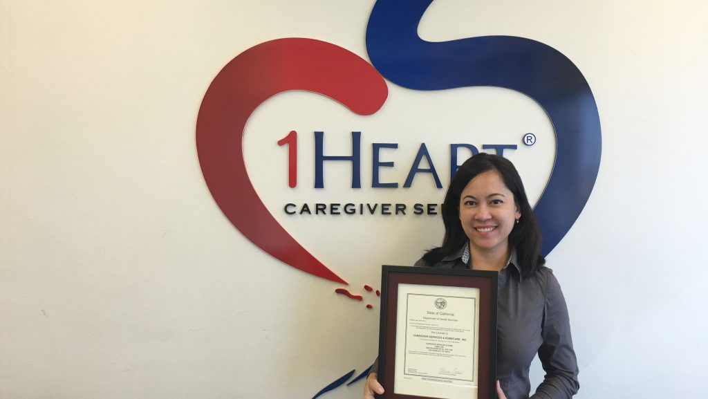 Picture of Belina holding the HCO License issued to 1Heart Caregiver Services