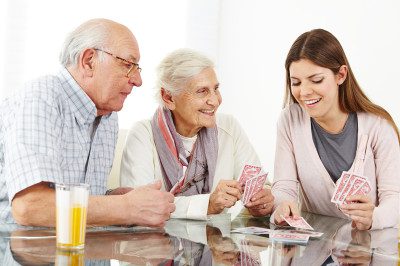 A young woman playing cards with an elderly couple