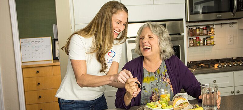 Senior enjoys being provided meal assistance by a 1Heart Caregiver.