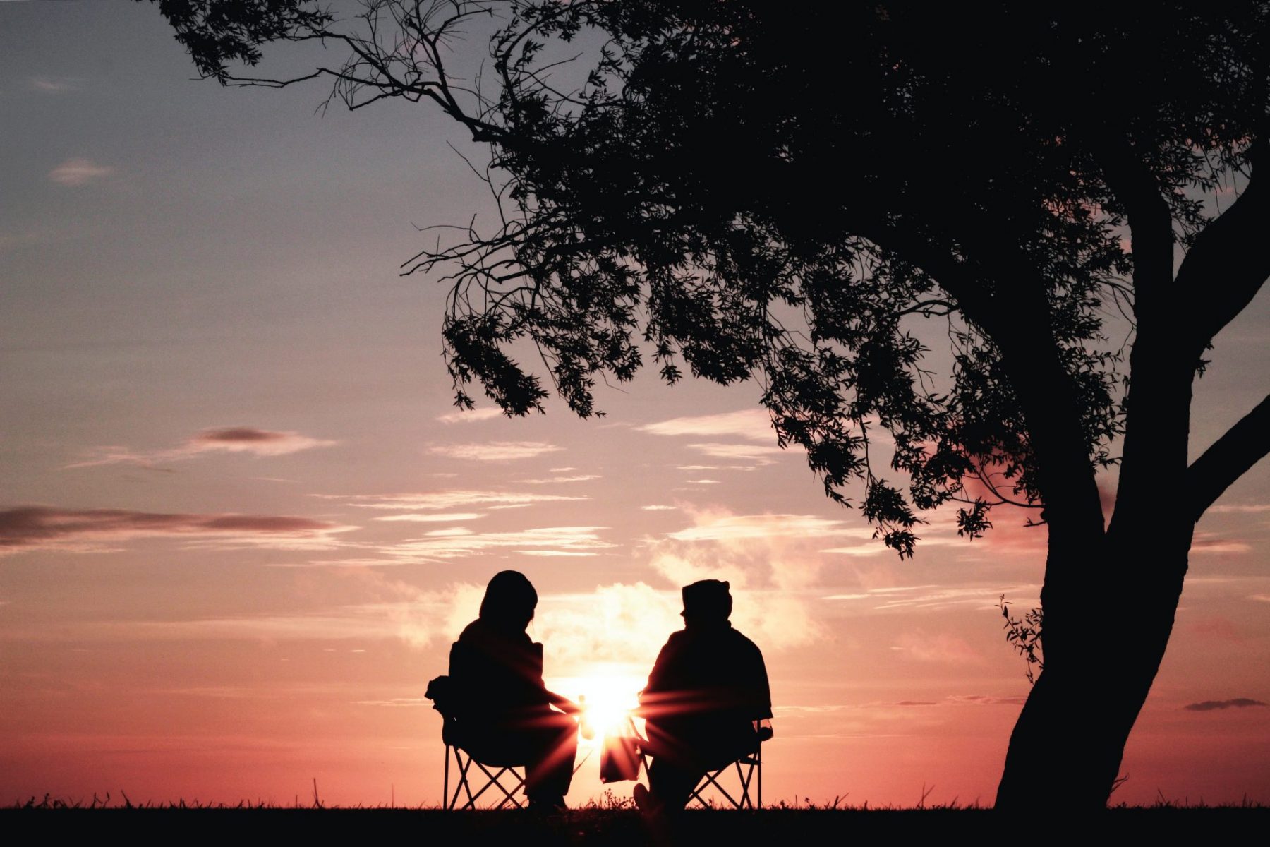older couple sitting in the sunset silhouette