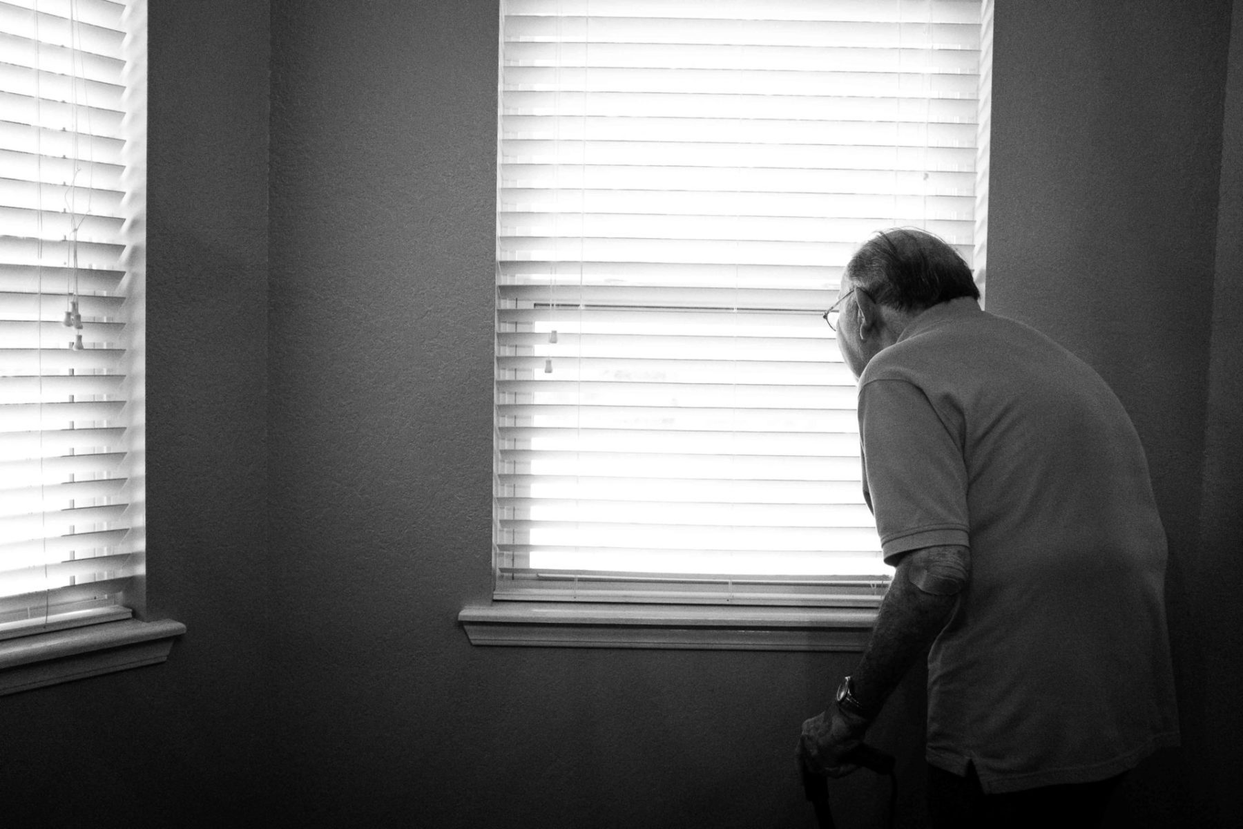 senior left alone looking outside the window