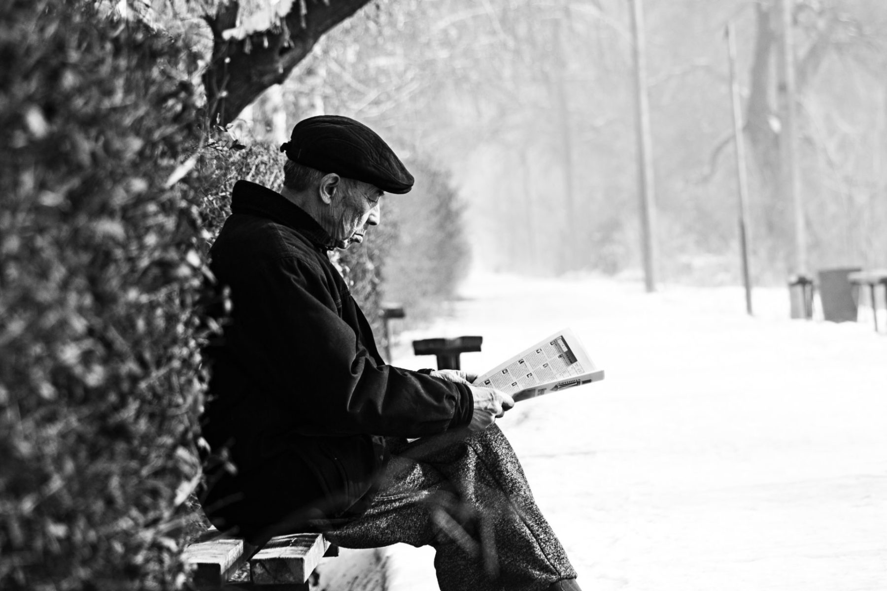 senior man reading outside in cold weather