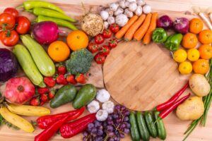A colorful blend of fruits and vegetables on a wooden table - a composition of carrots, pomegranates, strawberries, avocados, mushrooms, oranges, and more!