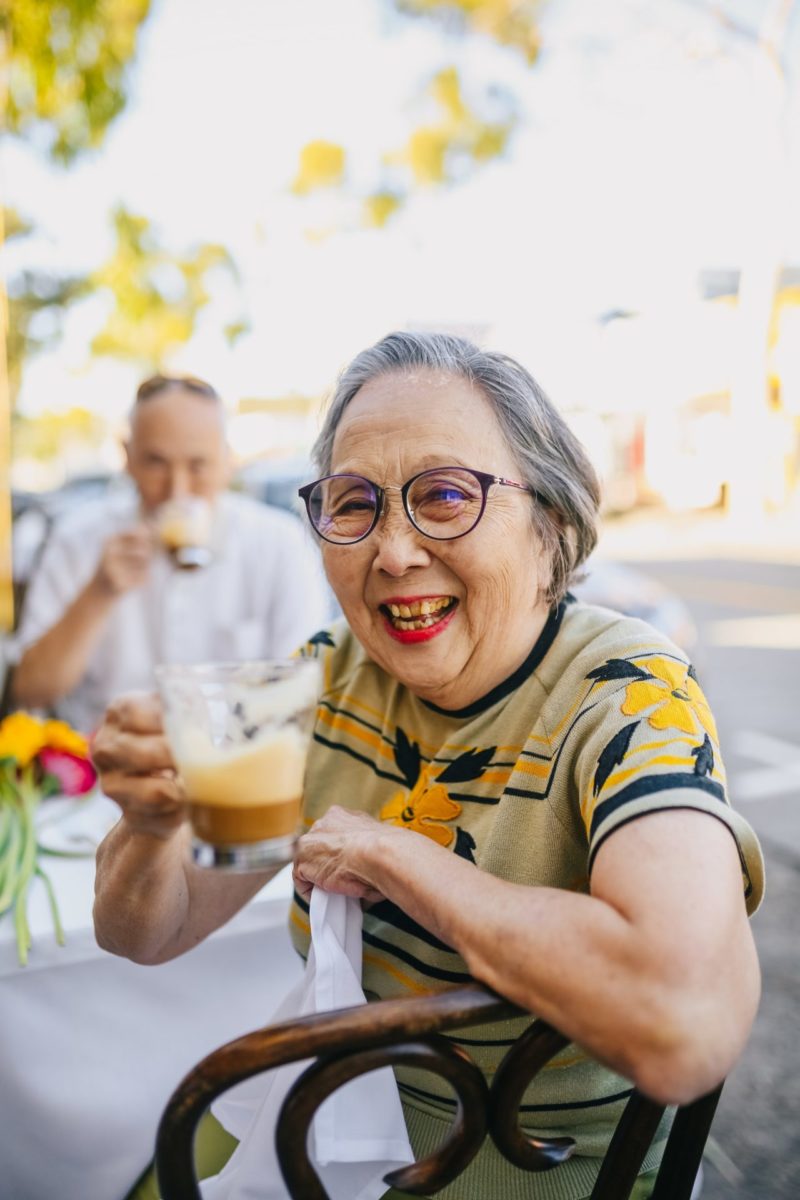 An elderly woman drinks a cup of coffee.