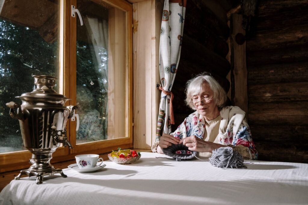 Grandmother knitting by the cabin window