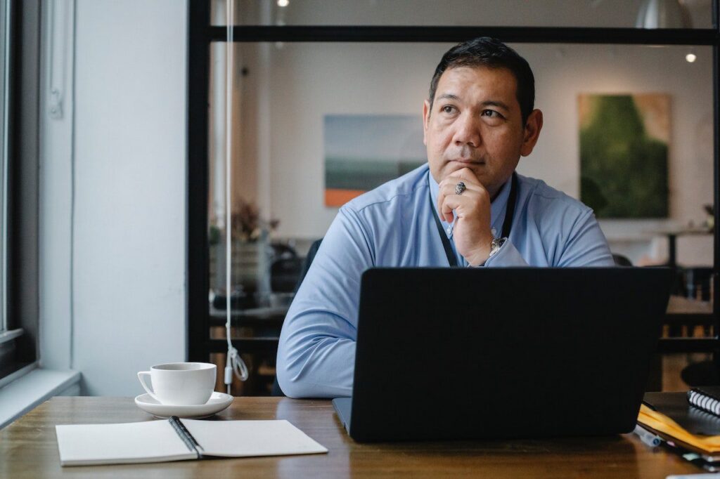 Man with a worried expression, looks out a window.