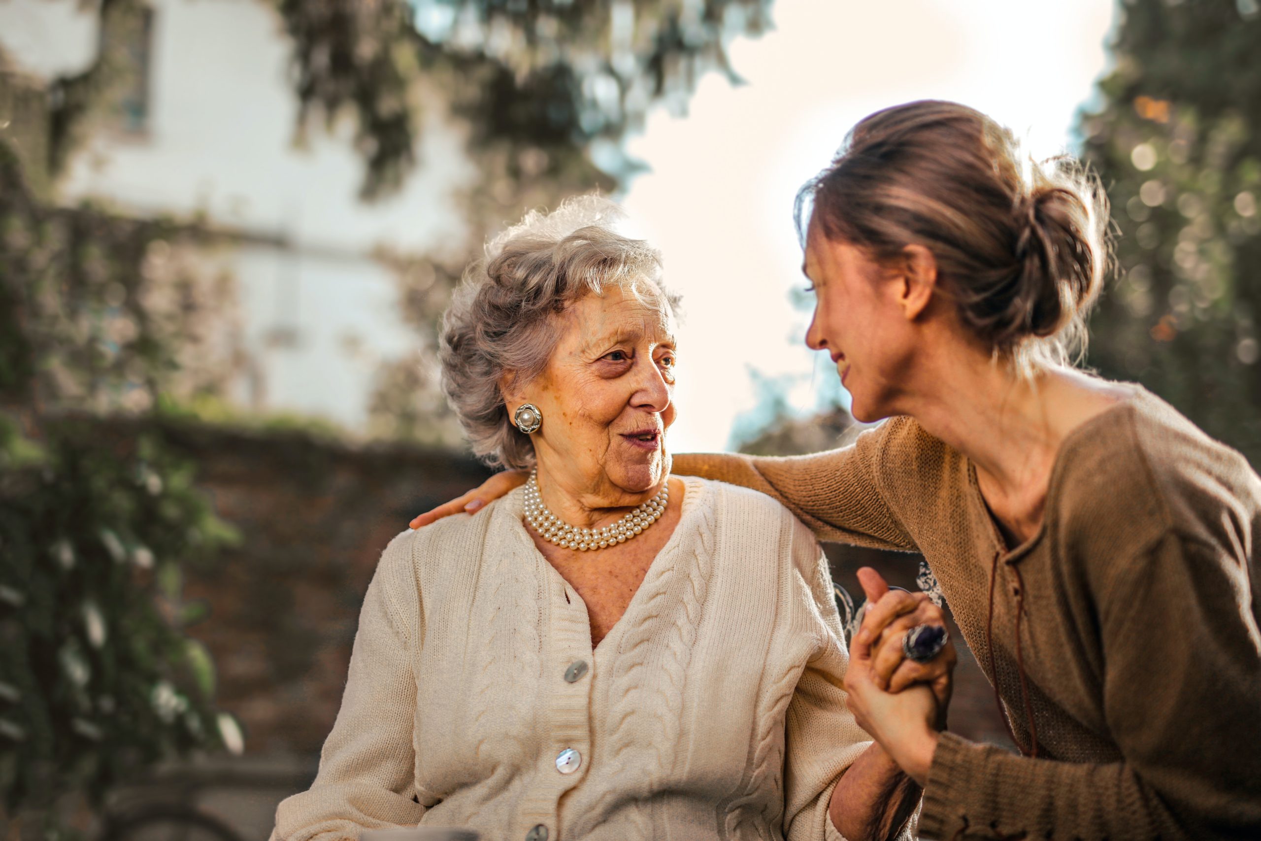 A home care worker and elderly patient sit outside