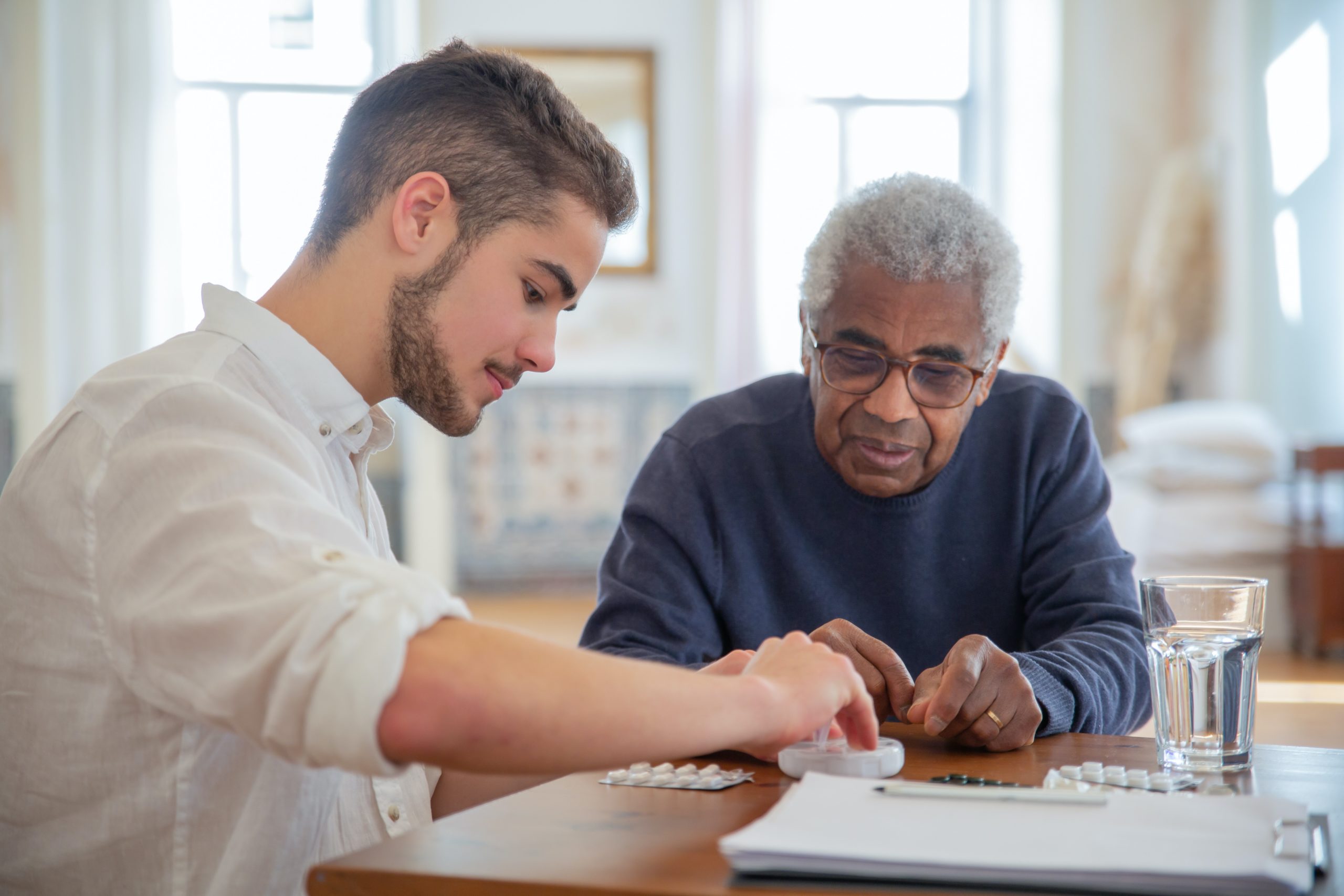 An elderly man reviews medication with a home care worker