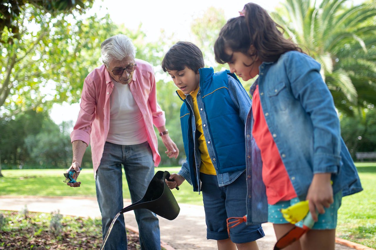 Photo of a senior planting a spring garden with young children