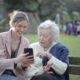 A caregiver and a woman with dementia look at photos on a smartphone