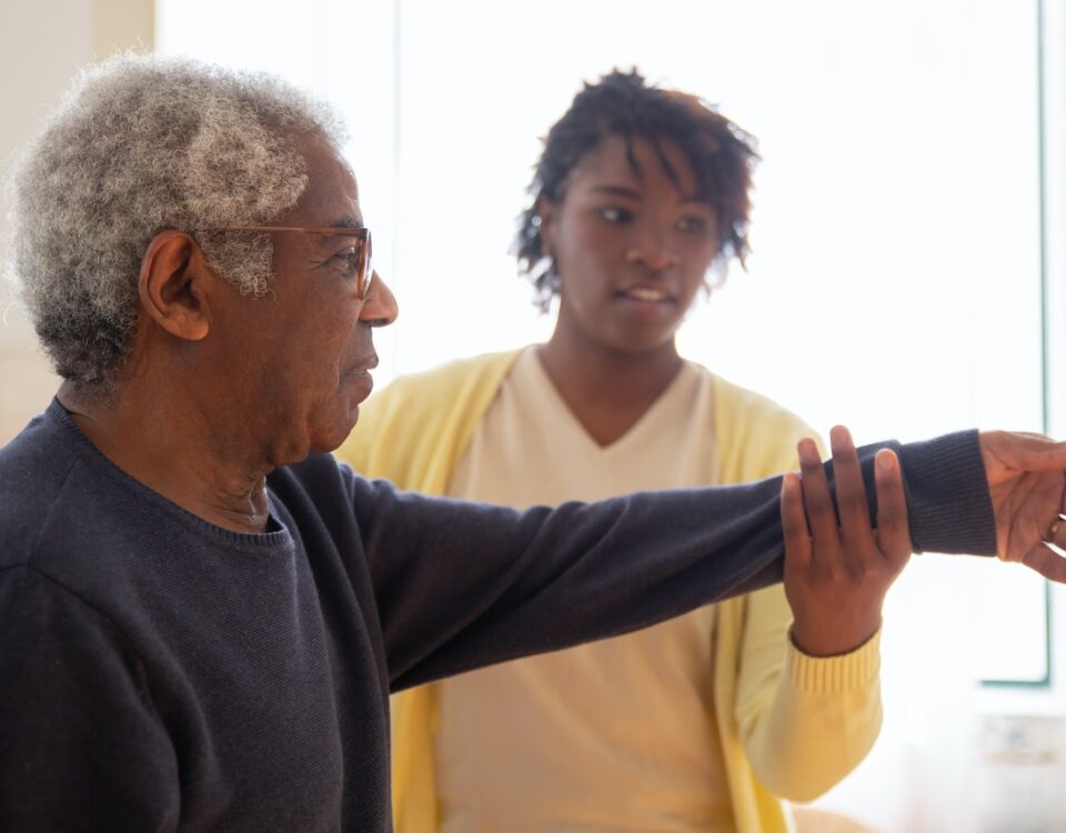 A caregiver helps an elderly client with rehab exercises after surgery.