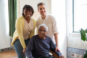 An adult child, their elderly parent, and a professional caregiver pose for a photo.