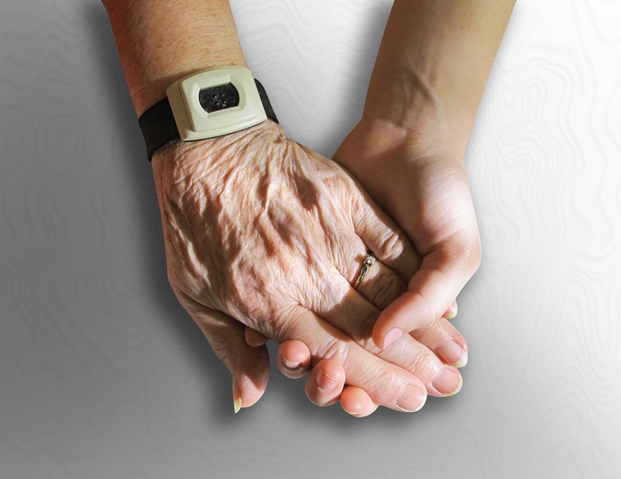 A senior care worker holding an elderly man’s hand.