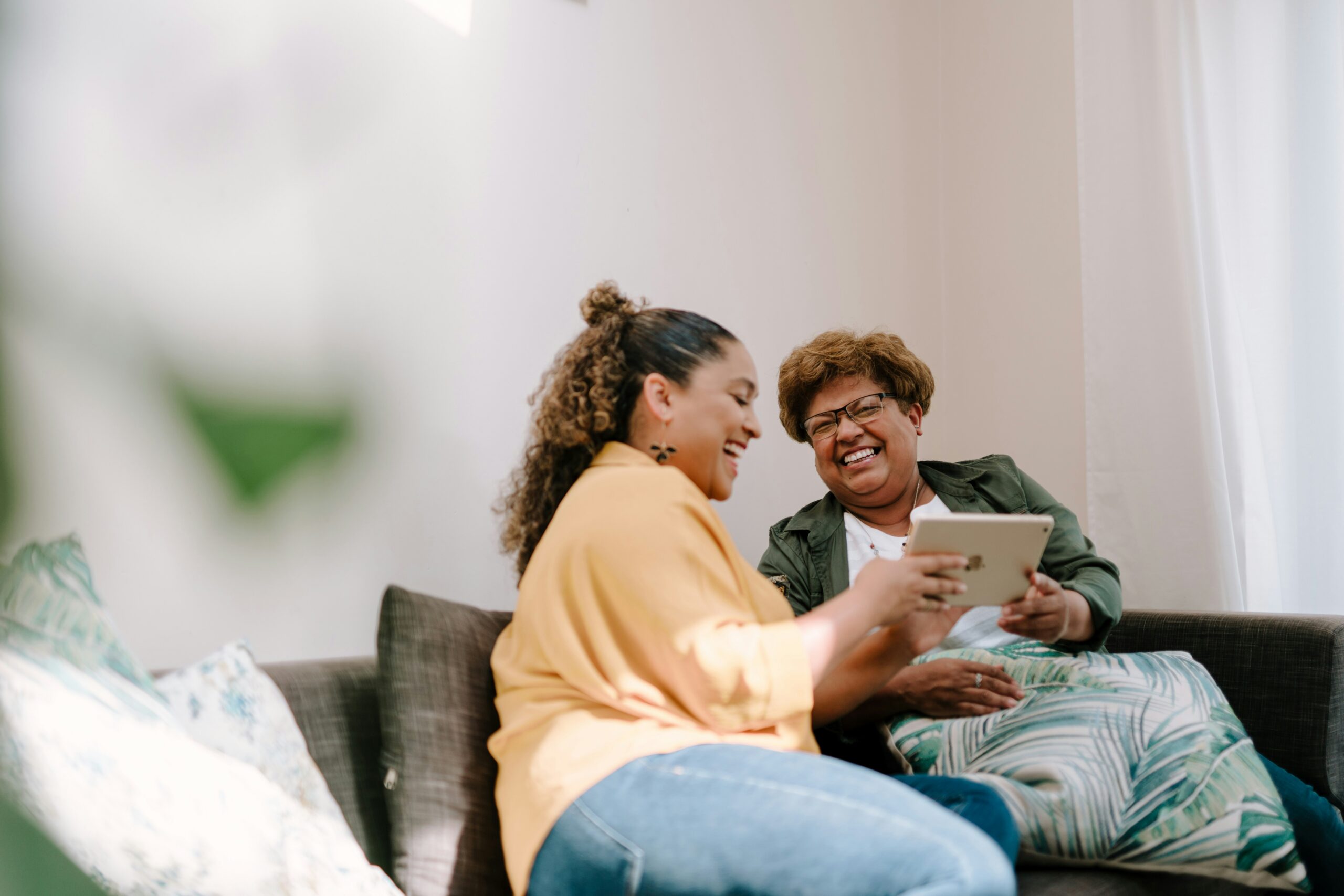A caregiver showing an elderly woman how to use an iPad